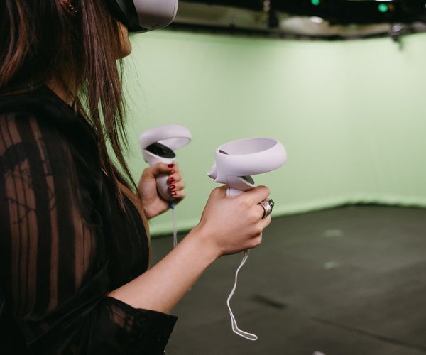 Student using a VR headset in a green screen room.