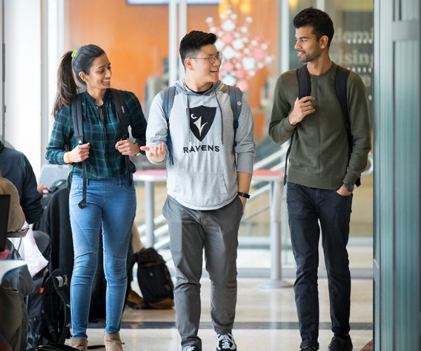 Three students walking and chatting.