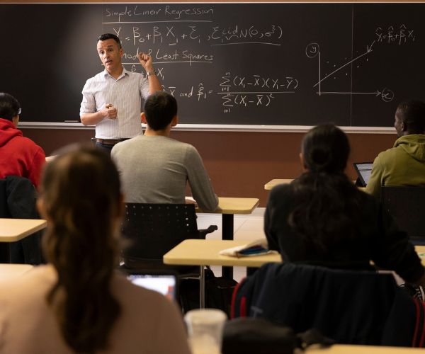 Statistics professor teaching a lecture in front of a group of students.