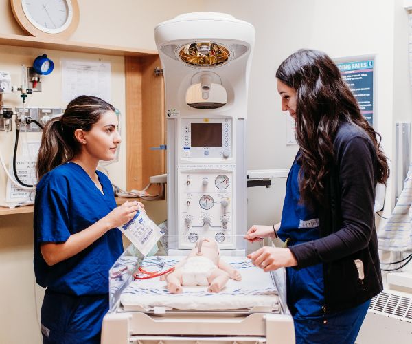 Two nurses training on medical simulation in a hospital.