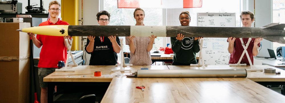 Engineering students displaying a high-powered rocket.