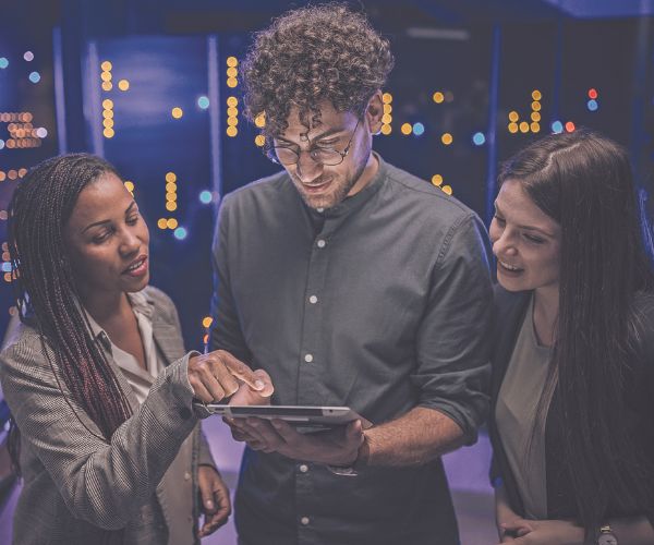 Professor and students in a computer server room looking at a laptop.