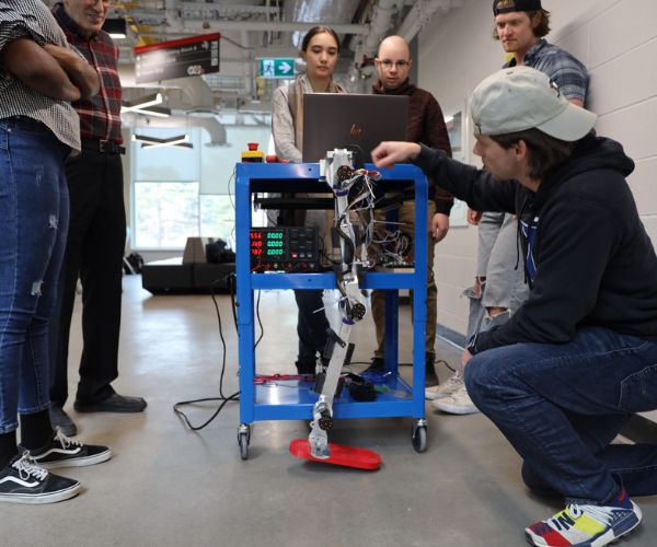 Students and a professor working on a robot.