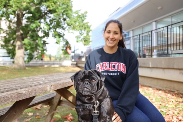 Carleton therapy dog and handler at a picnic table in the Academic Quad.