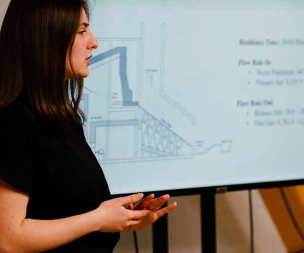 Photo of a women in-front of a tv presenting a slide show. 
