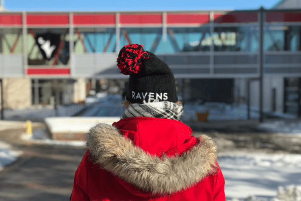 Person wearing a winter hat outside of the Athletics building on the Carleton campus.