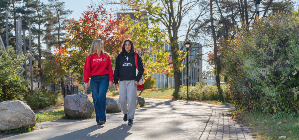 Two students walking on a path on the Carleton University campus in the fall.