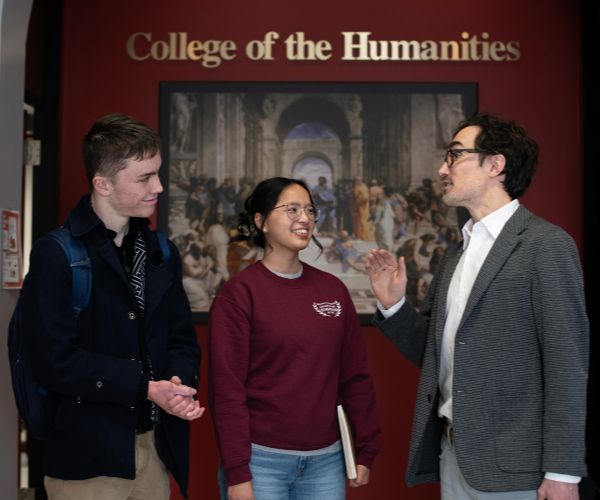 Professor and students chatting in the College of the Humanities.