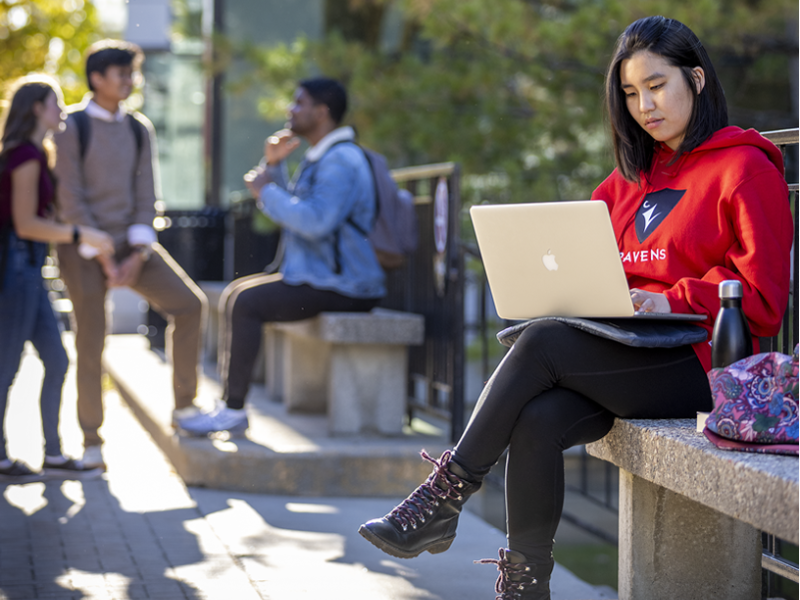 Student with a laptop in the quad.